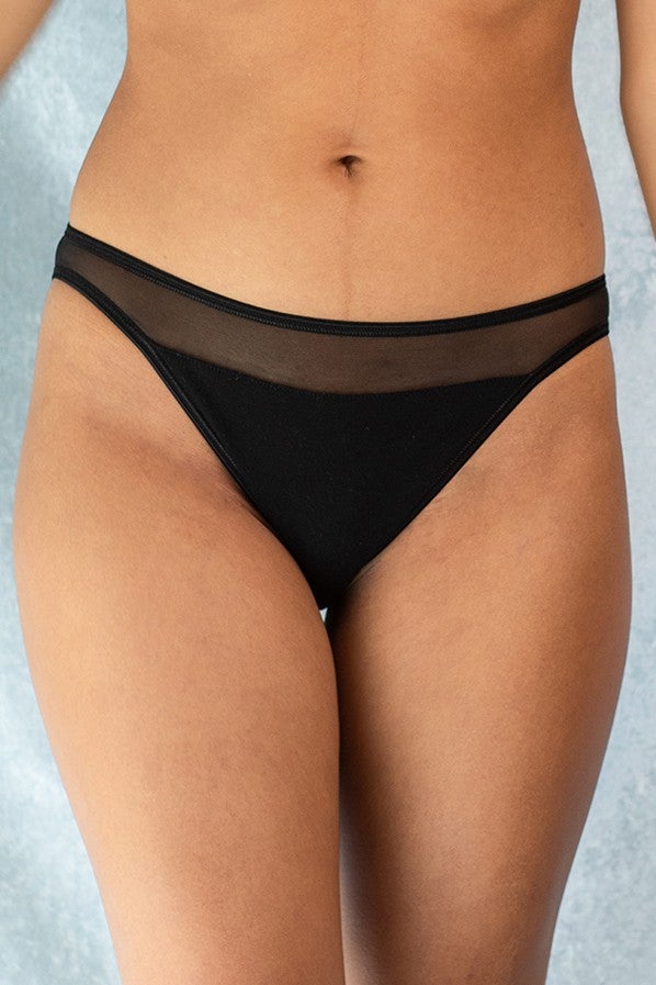 Jeune femme qui porte une culotte noire de la marque Olly lingerie, sexy et confortable.