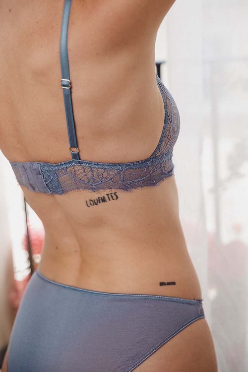 Une jeune femme porte une culotte et un bustier en dentelle recyclée de couleur bleue.