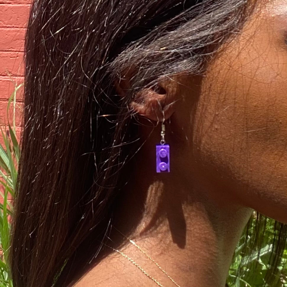 Boucles d'oreilles pendantes argentées avec brique Lego® violette, ajoutant une touche colorée à votre look.