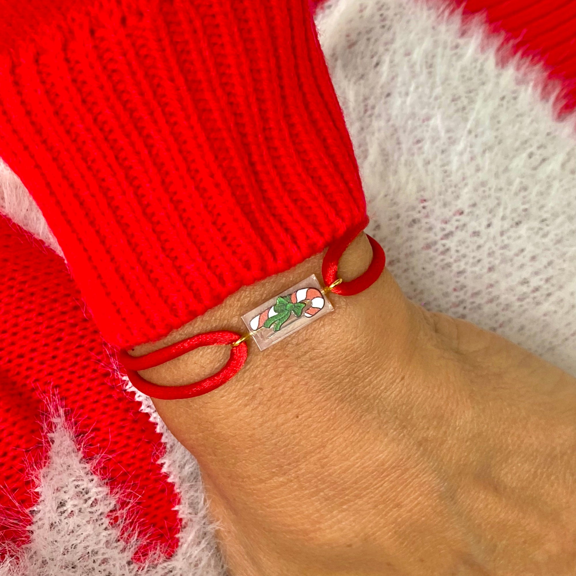 Bracelet spécial Noël avec un sucre d'orge imprimé sur une brique de Lego authentique. Le bracelet se règle avec un cordon rouge soyeux ajustable coulissant facilement.