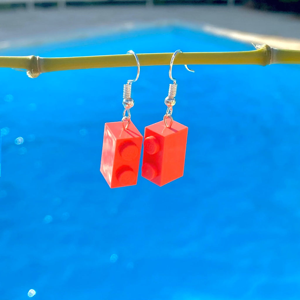 Boucles d'oreilles pendantes en brique Lego rose corail, créées pour ajouter une touche colorée et fun à votre look.
