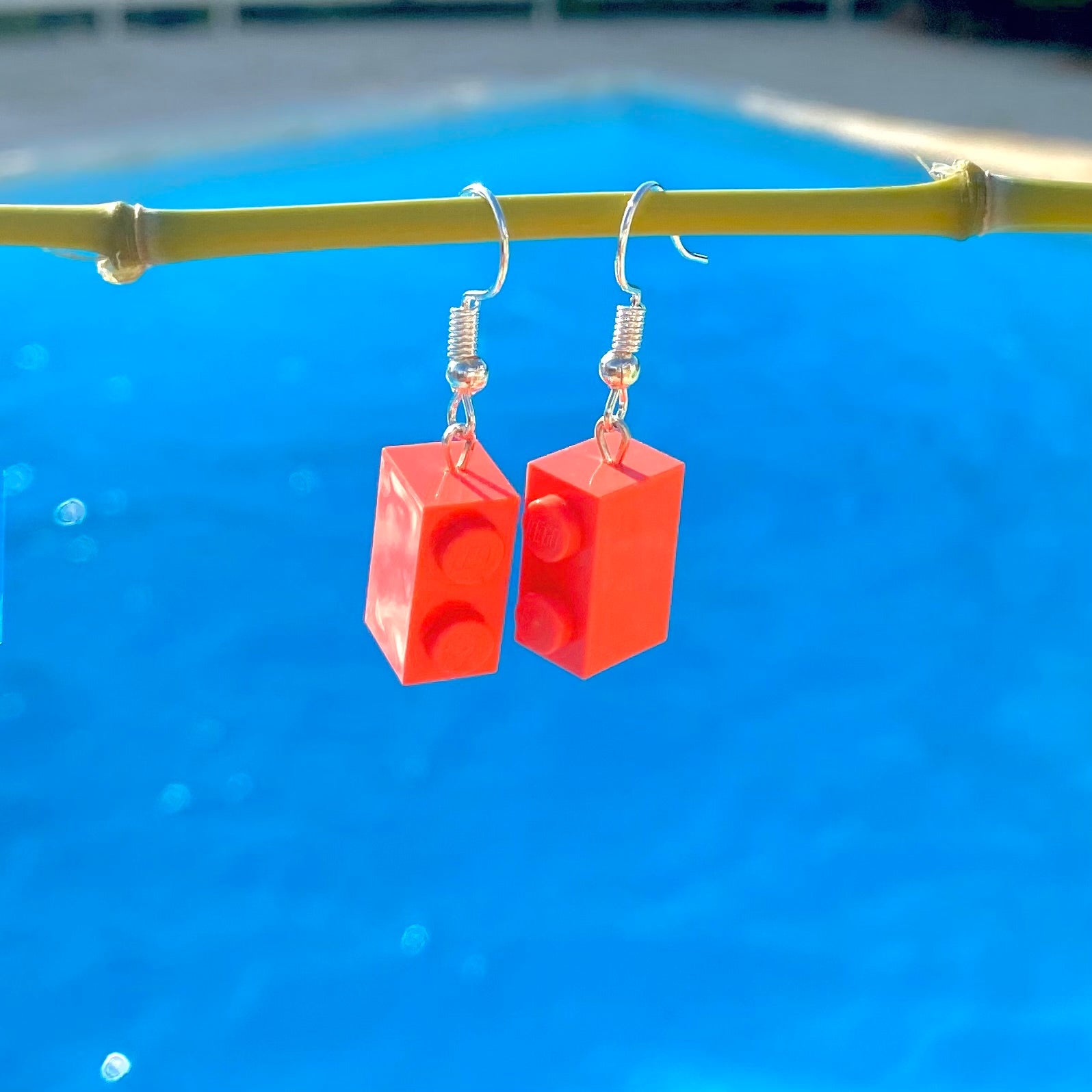 Boucles d'oreilles pendantes en brique Lego rose corail, créées pour ajouter une touche colorée et fun à votre look.
