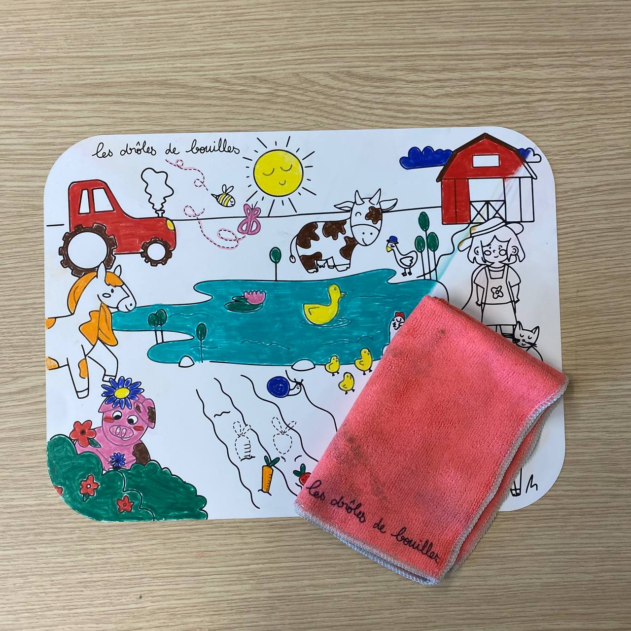 Set de table sur le thème des animaux de la ferme colorié et à moitié effacé avec une lavette rose humide